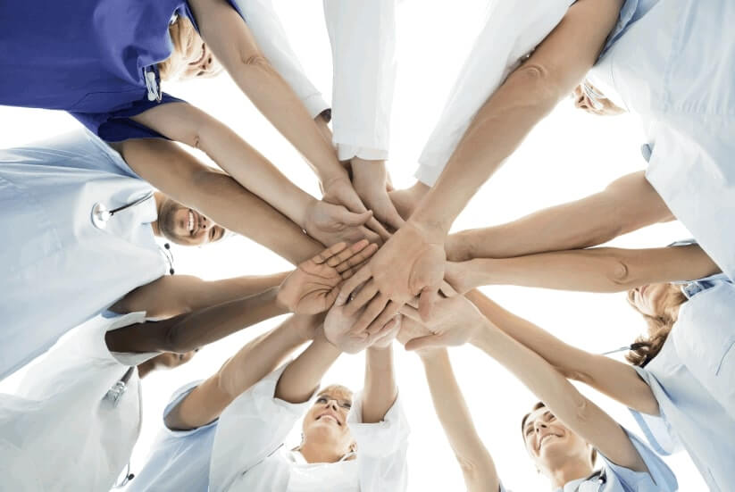 A group of people holding hands in the middle of a circle.